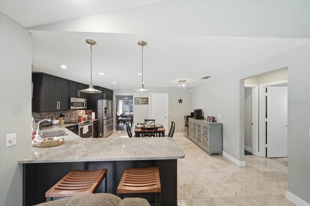 A kitchen with dark cabinets, granite countertops, and a dining area with tile flooring — 11803 SWEETPEA COURT, TAMPA, FL