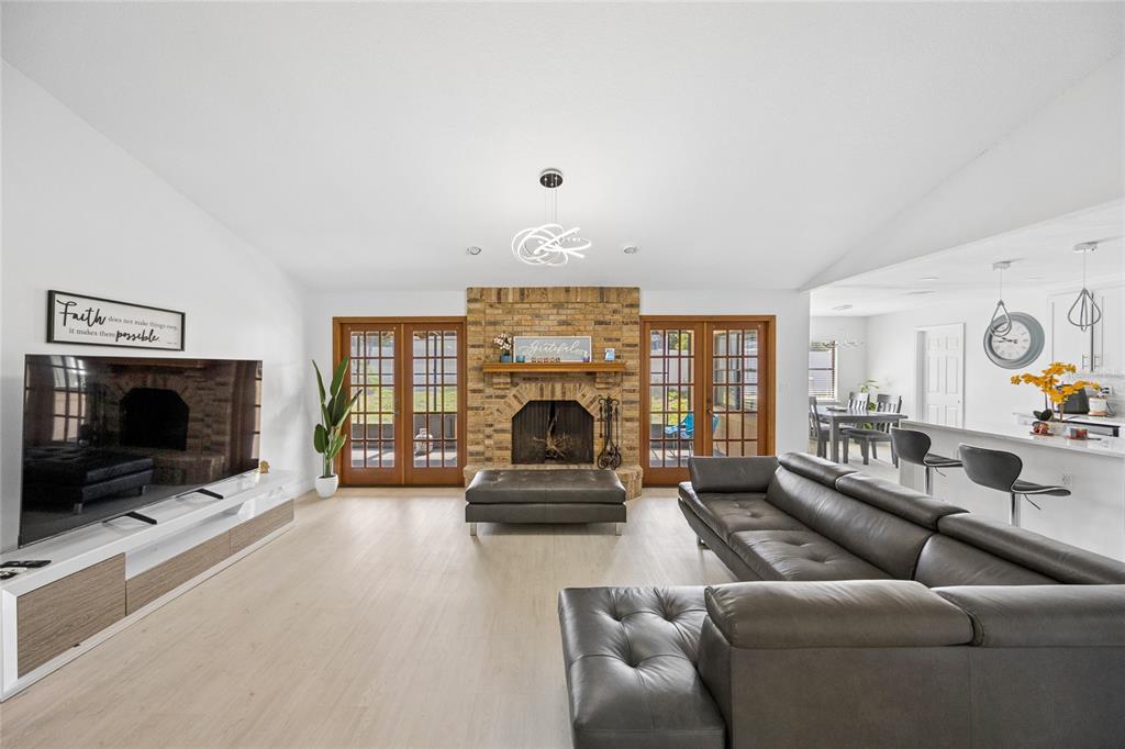 A living room features a brick fireplace, leather sectional, light wood floors, and glass doors — 733 SAXBY AVENUE, ORLANDO, FL