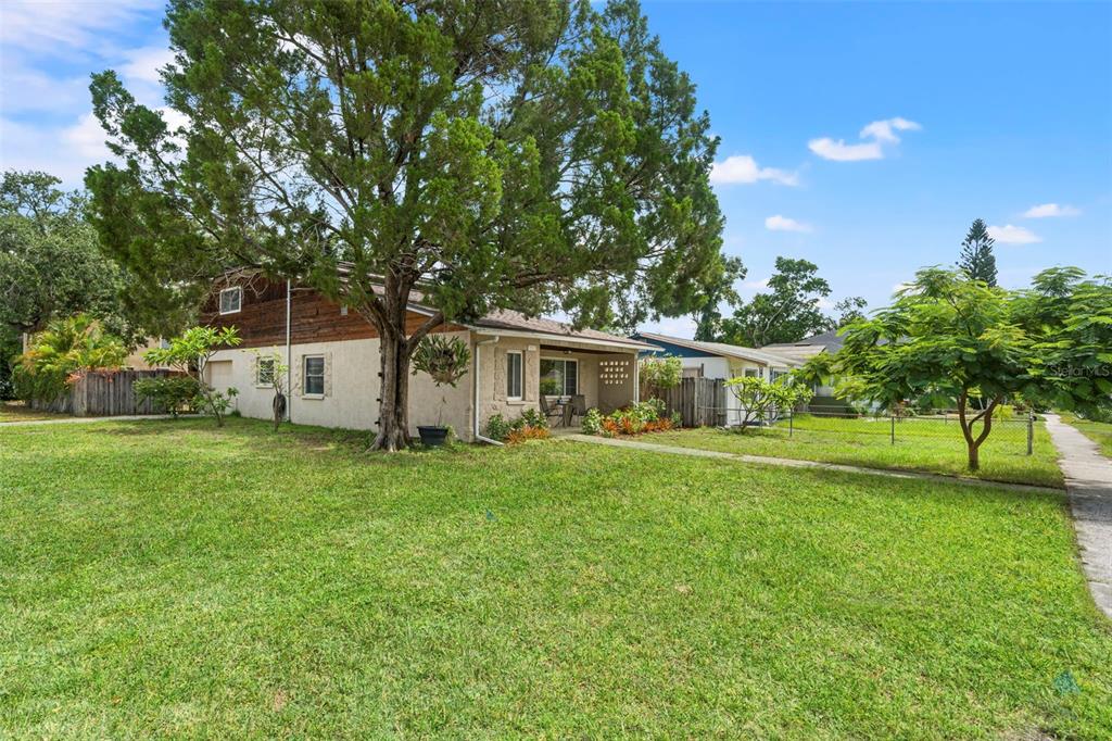 A single-story house with a tan stucco exterior, wood siding, and a front porch — 2355 14TH AVENUE N, ST PETERSBURG, FL