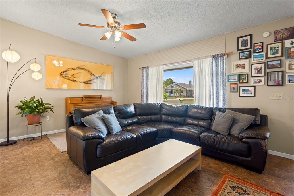 A living room features a large black leather sectional, a coffee table, and a gallery wall — 2355 14TH AVENUE N, ST PETERSBURG, FL
