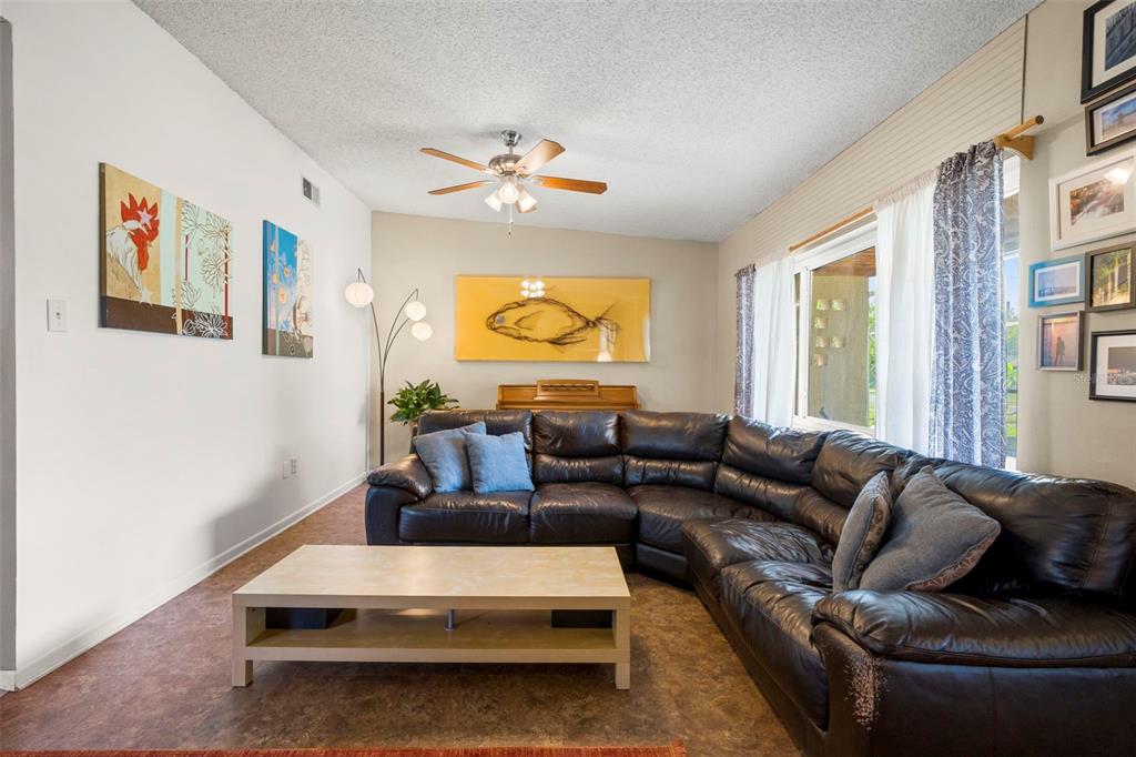 A living room features a large dark leather sectional, a coffee table, and wall art — 2355 14TH AVENUE N, ST PETERSBURG, FL