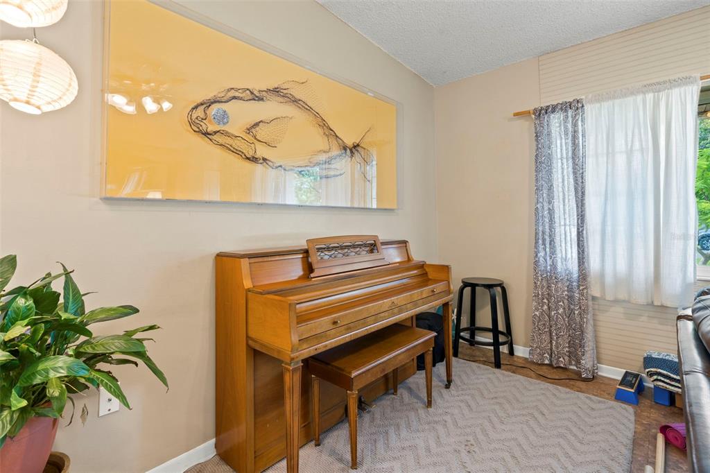 A room features a wooden upright piano, a large fish artwork, and a patterned rug — 2355 14TH AVENUE N, ST PETERSBURG, FL