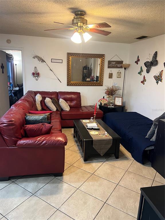 A living room features a red sectional sofa, a black coffee table, and tile flooring — 437 HUNTER CIRCLE, KISSIMMEE, FL