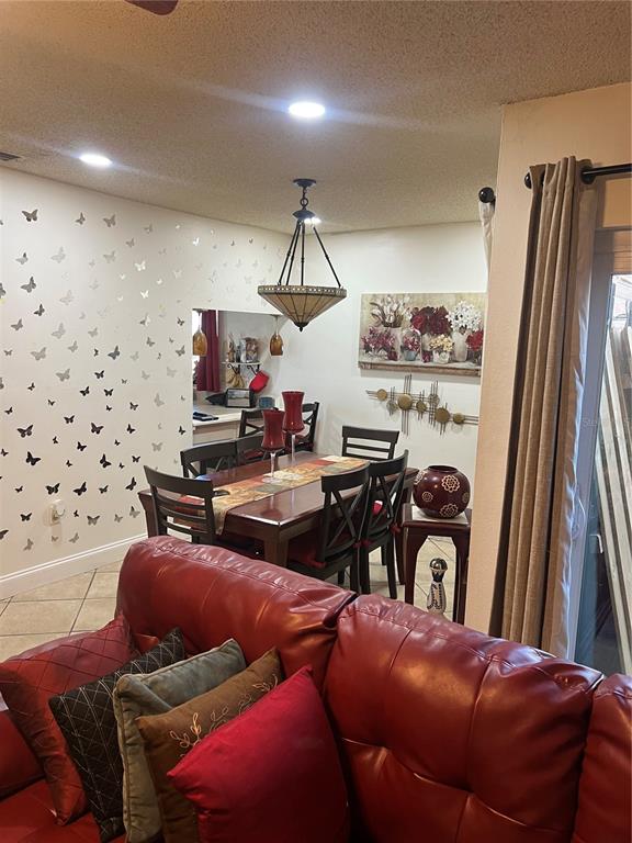 A dining area with a butterfly-patterned wall, wooden table, and red leather sofa — 437 HUNTER CIRCLE, KISSIMMEE, FL