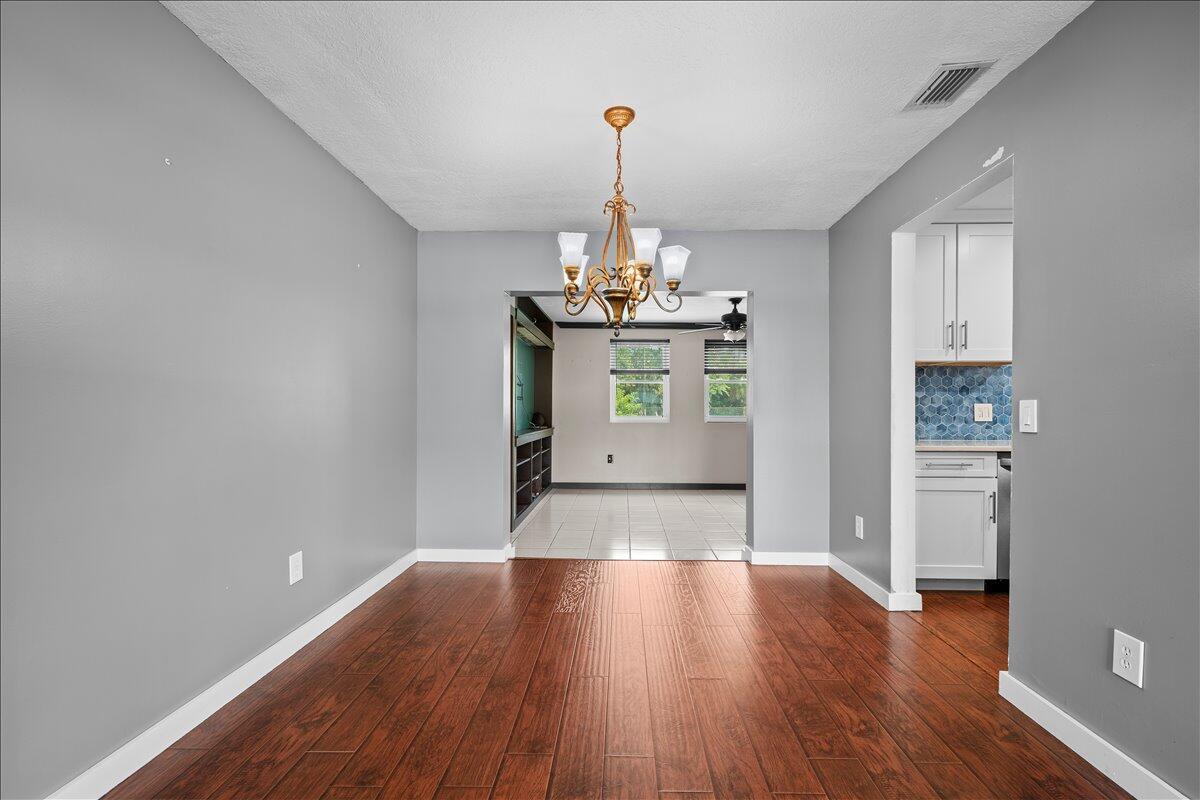 A dining room with hardwood floors, a chandelier, and an open doorway to another room — 7423 Oakmont Drive, FL 33467, FL