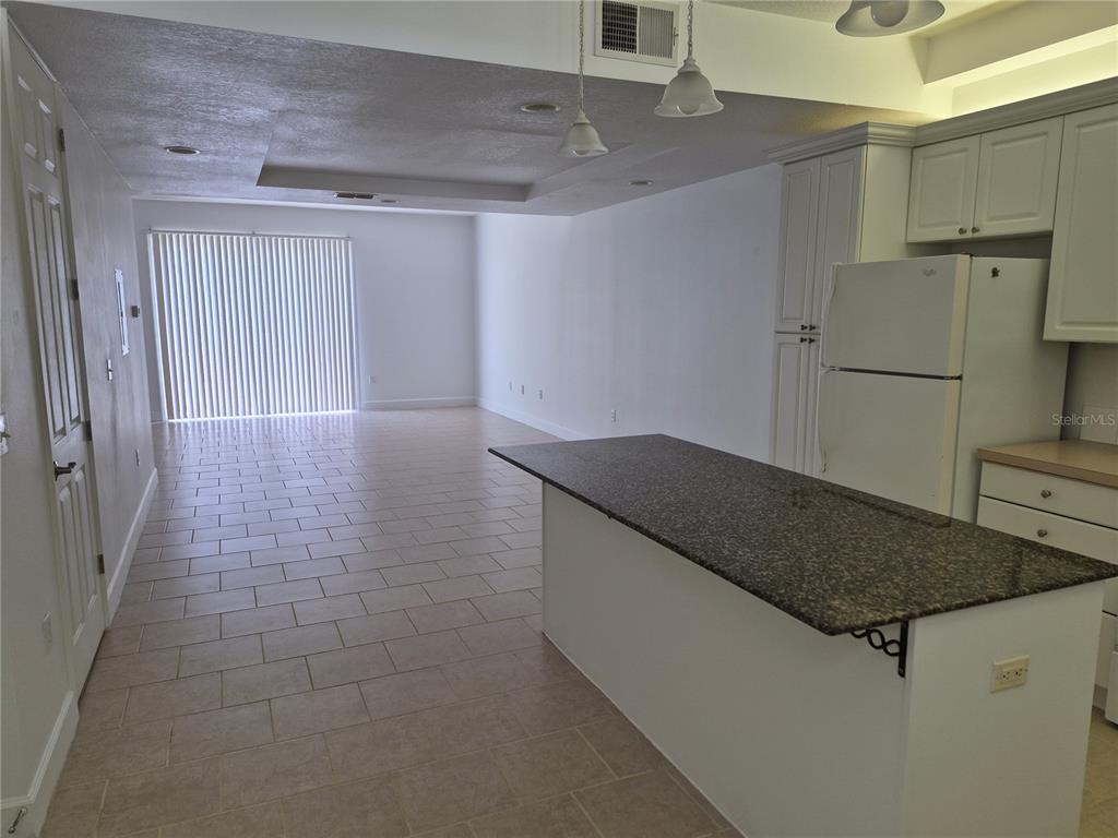 A kitchen with a granite-topped island and white cabinets overlooks an open living area — 2080 HERITAGE KEY BOULEVARD, KISSIMMEE, FL