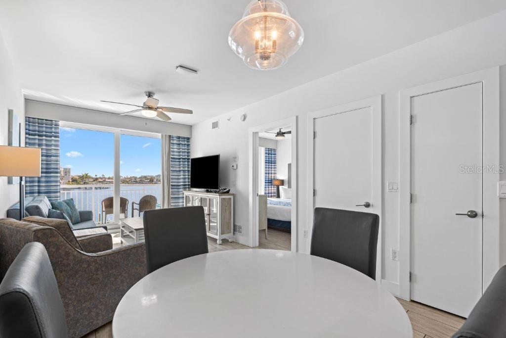 A dining area with a round table overlooks a balcony with a water view — 10091 GULF BOULEVARD UNIT 202E, TREASURE ISLAND, FL