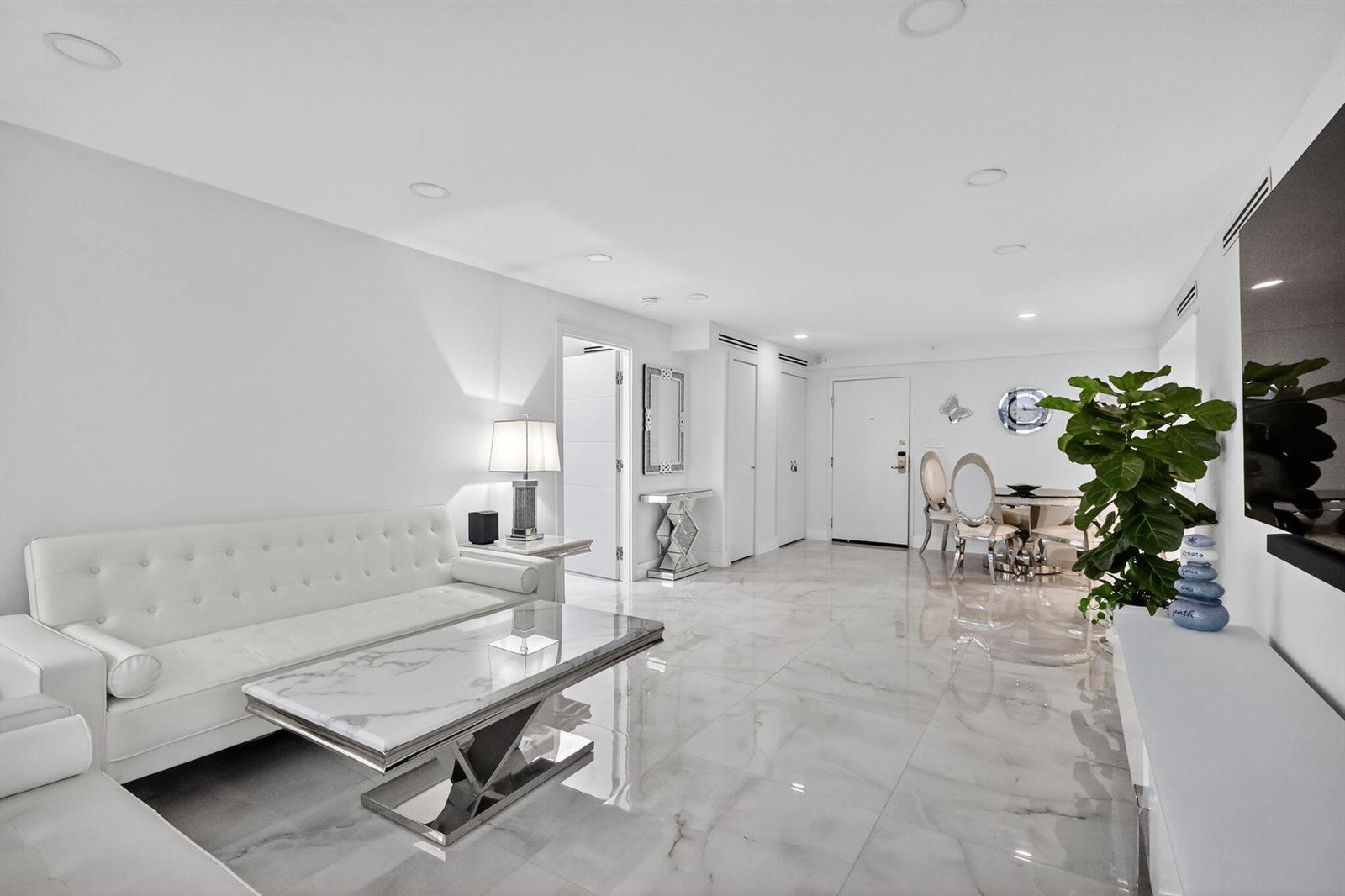 A modern living room features white leather furniture, a marble coffee table, and glossy tile floors — 5225 Collins Avenue # 1408, Miami Beach FL 33140, MIAMI BEACH, FL