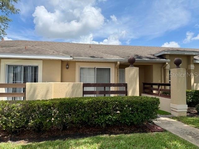 A single-story house exterior features a tan facade, a brown shingled roof, and a hedge — 3204 CRANES NEST LANE, KISSIMMEE, FL