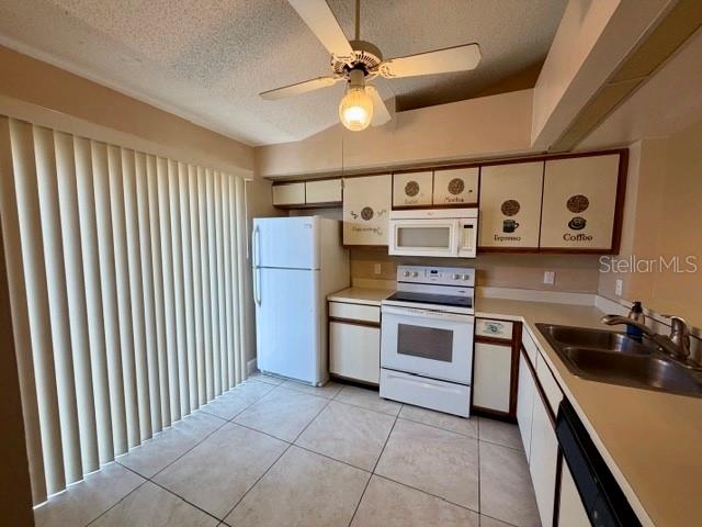 A kitchen features white appliances, light-colored cabinets, tile flooring, and a ceiling fan — 3204 CRANES NEST LANE, KISSIMMEE, FL