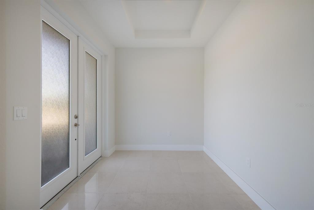 A bright entryway features white walls, tile flooring, a tray ceiling, and double glass doors — 6009 WHITE MANGROVE LANE, BRADENTON, FL