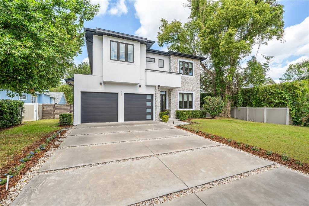 A two-story modern house with a concrete driveway, two-car garage, and stone accent wall — 2407 LAFAYETTE AVENUE, WINTER PARK, FL