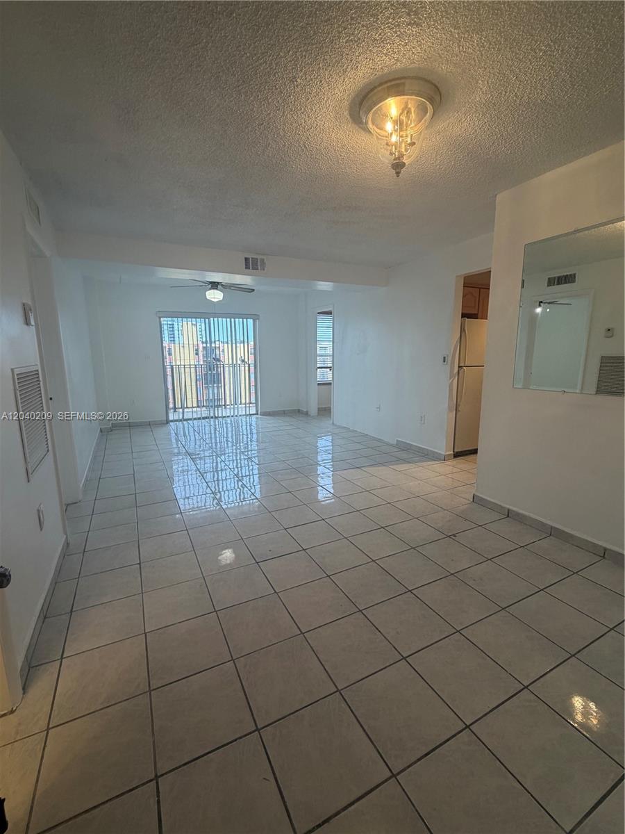 An open-concept living and dining area features white tile flooring and a sliding glass door — 4717 NW 7th St # 10, Miami FL 33126, MIAMI, FL