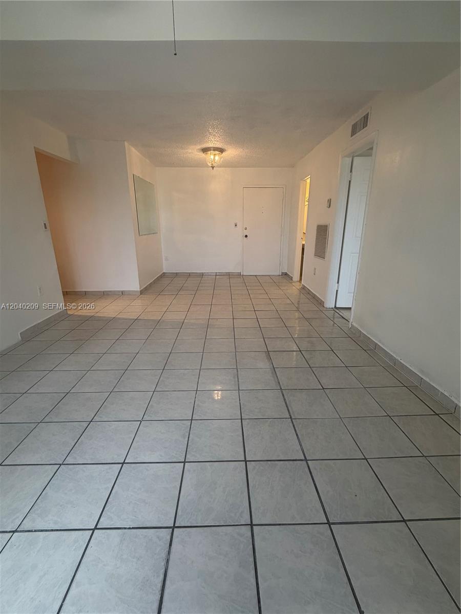 An empty room features light-colored square floor tiles, white walls, and a central ceiling light — 4717 NW 7th St # 10, Miami FL 33126, MIAMI, FL