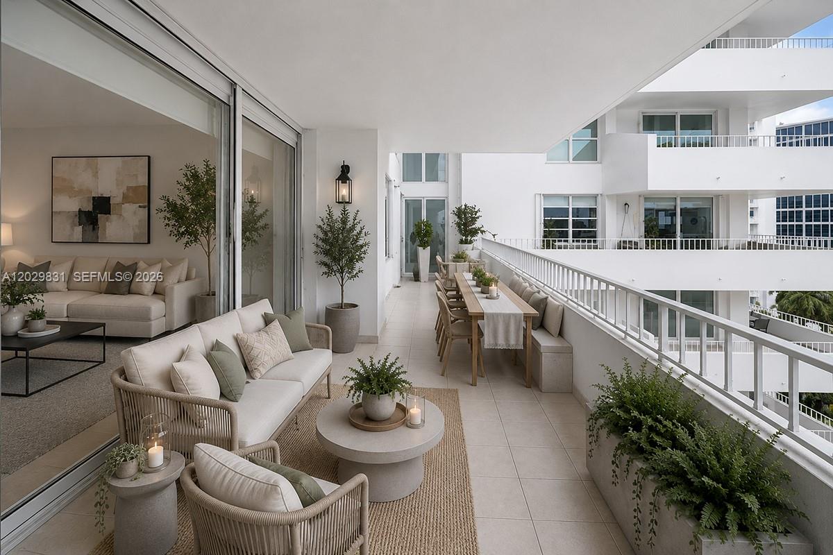 A spacious balcony features outdoor seating, a dining table, and potted plants overlooking a courtyard — 199 Ocean Lane Dr # 911, Key Biscayne FL 33149, KEY BISCAYNE, FL