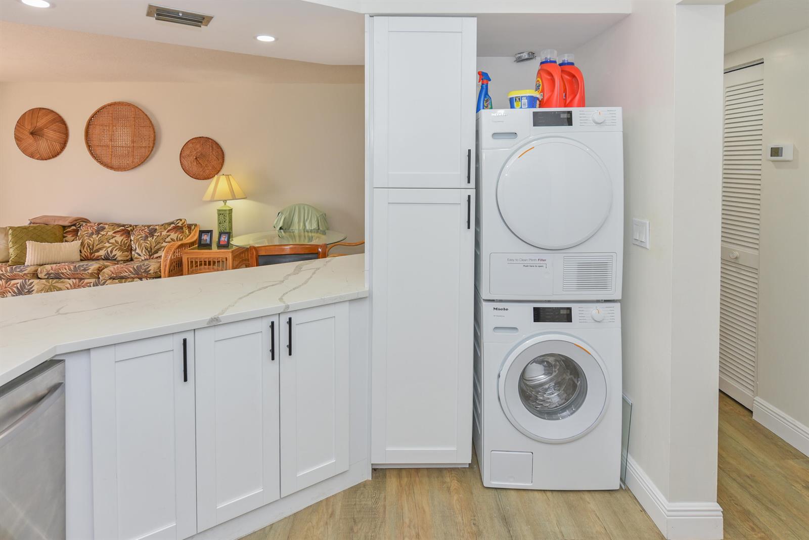 A white kitchen counter sits next to a stacked Miele washer and dryer unit — 1605 Us-1 # D305, Jupiter FL 33477, JUPITER, FL