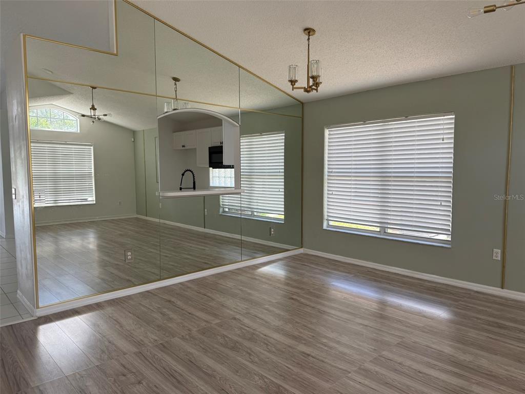 A dining area features wood-look flooring, light green walls, and a large mirrored accent wall — 1026 LAKE DAVENPORT BOULEVARD, DAVENPORT, FL