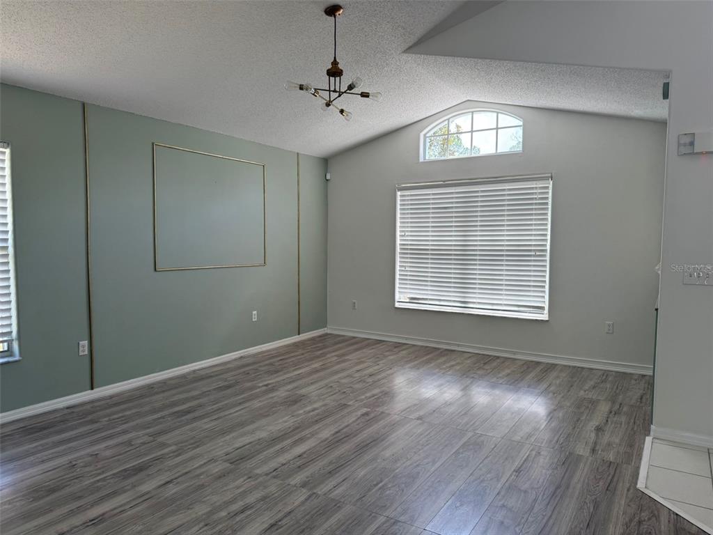 A living room features light green walls with gold trim, wood-look flooring, and a vaulted ceiling — 1026 LAKE DAVENPORT BOULEVARD, DAVENPORT, FL