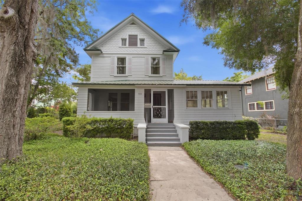 A two-story white house with a screened front porch and a concrete walkway — 533 N SANS SOUCI AVENUE, DELAND, FL