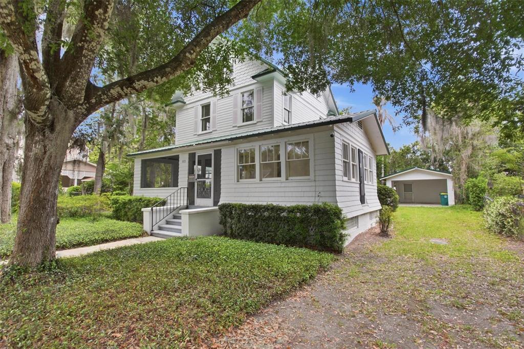 A two-story white house with a front porch, shingle siding, and a detached garage — 533 N SANS SOUCI AVENUE, DELAND, FL