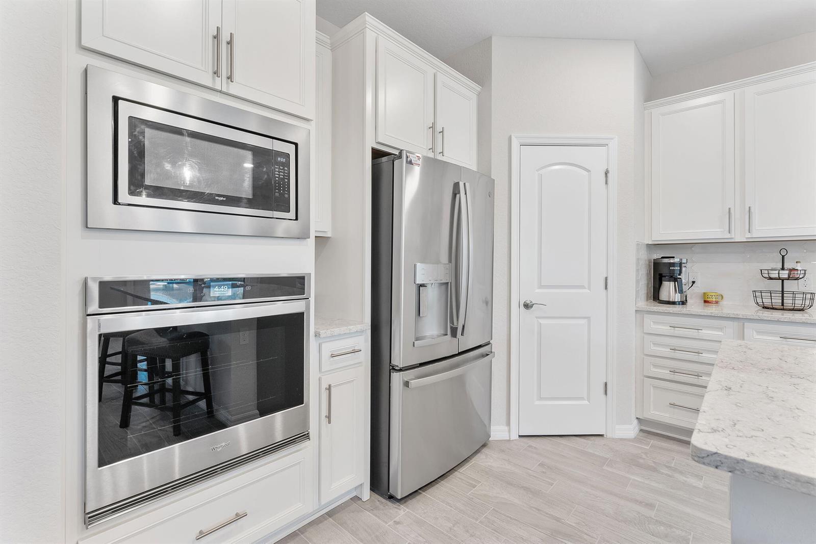 A kitchen features white cabinetry, stainless steel appliances, and light-colored tile flooring — 8623 Patron Lane, Lake Worth FL 33467, LAKE WORTH, FL