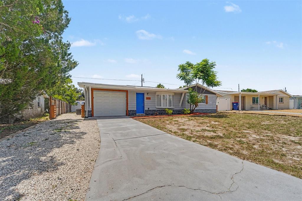 A single-story house with a blue front door, a garage, and a concrete driveway — 3555 SHERYL HILL DRIVE, HOLIDAY, FL
