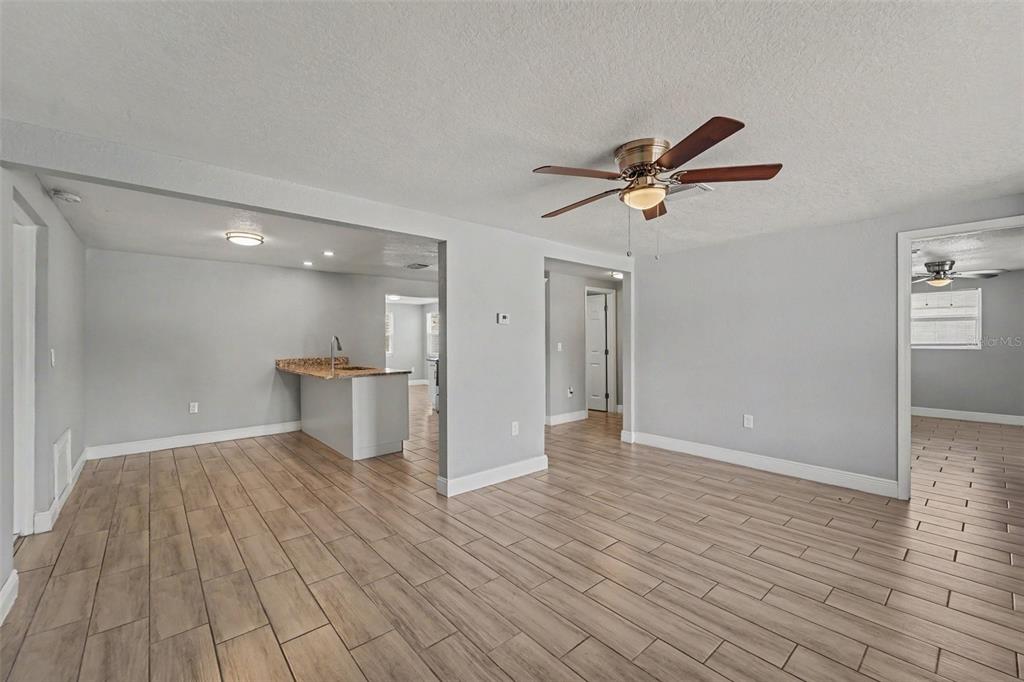 An open-concept living area features light gray walls, wood-look tile flooring, and a ceiling fan — 3555 SHERYL HILL DRIVE, HOLIDAY, FL