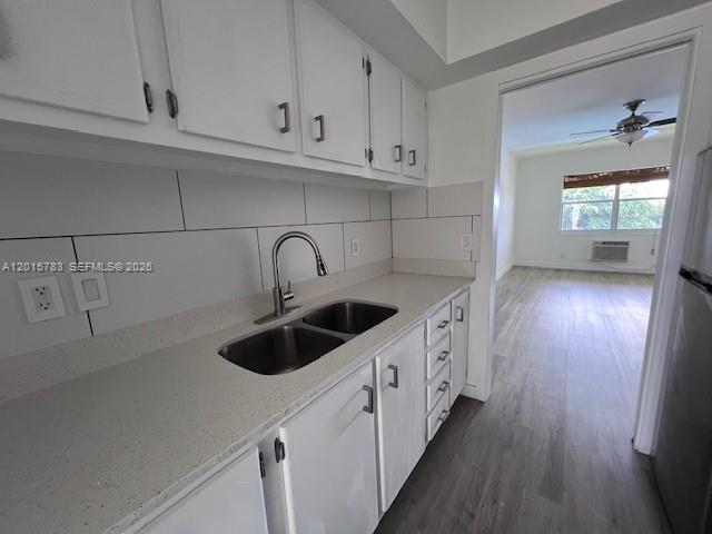 A kitchen features white cabinets, a double-basin sink, and light countertops, opening into a living area — 1350 E Sample Rd # 306, Pompano Beach FL 33064, POMPANO BEACH, FL
