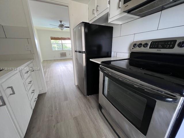 A kitchen features stainless steel appliances, white cabinetry, and light wood-look flooring — 1350 E Sample Rd # 306, Pompano Beach FL 33064, POMPANO BEACH, FL