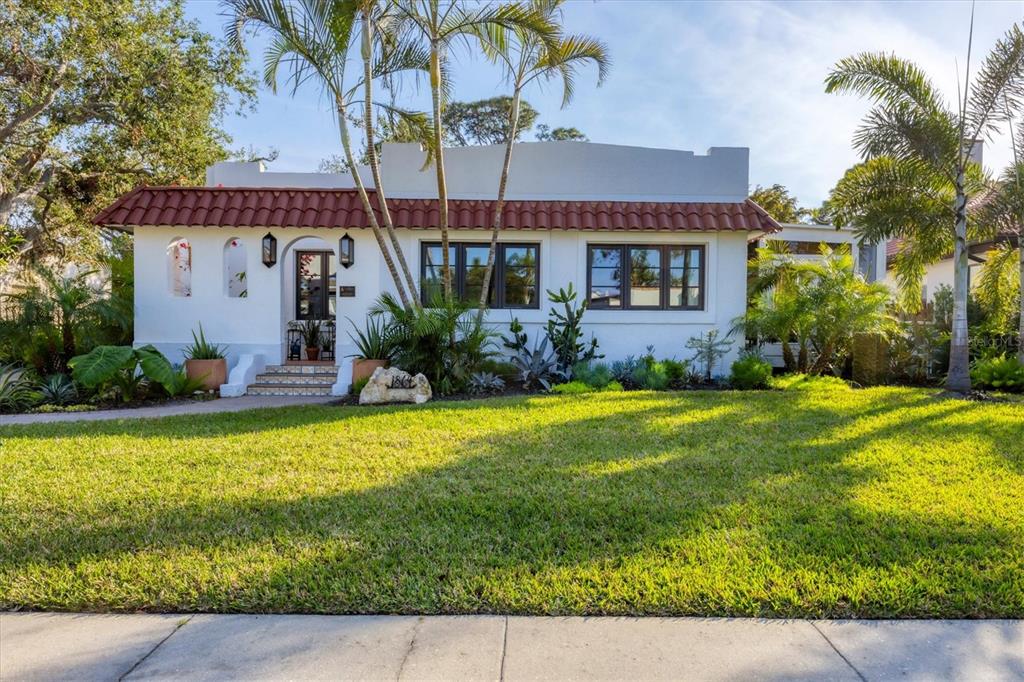 A single-story white stucco house with a red tile roof and palm trees in front — 1864 CLEMATIS ST STREET, SARASOTA, FL