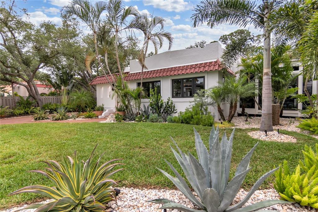 A white stucco house with a red tile roof sits behind a landscaped front yard — 1864 CLEMATIS ST STREET, SARASOTA, FL