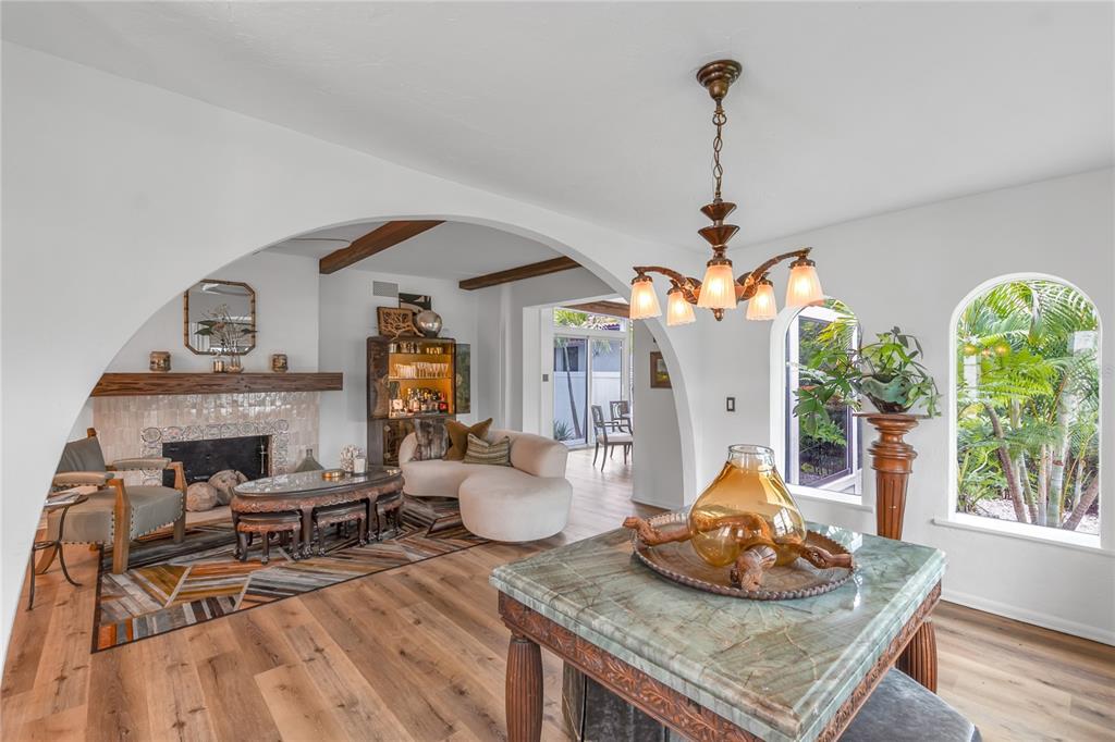 A living room with a fireplace, arched doorways, wood floors, and a stone-topped table — 1864 CLEMATIS ST STREET, SARASOTA, FL
