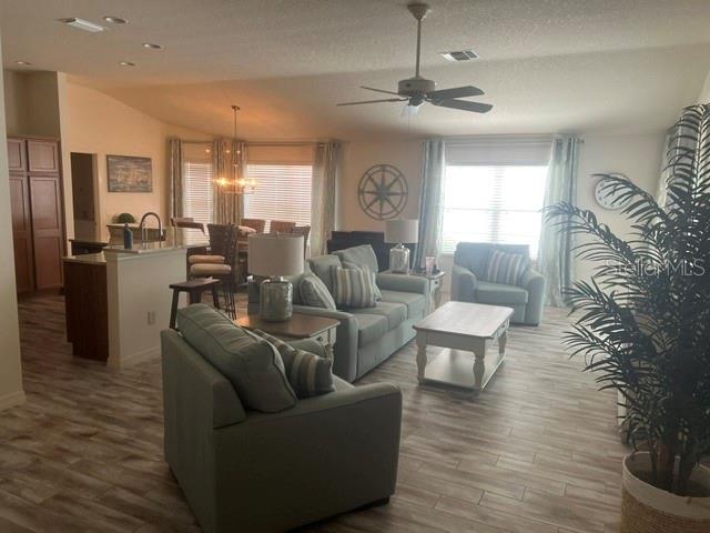 An open-concept living room and kitchen feature light wood flooring and blue upholstered furniture — 1101 SOUTHERN SUN DRIVE, THE VILLAGES, FL
