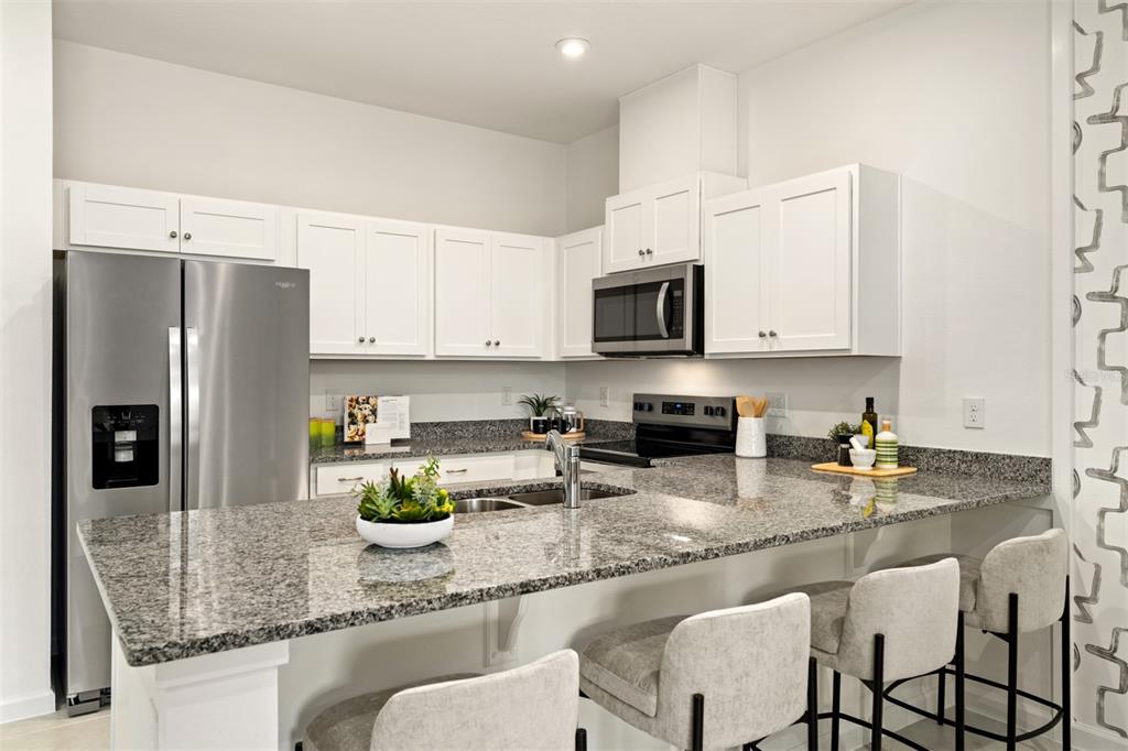 A kitchen features white cabinets, granite countertops, stainless steel appliances, and a breakfast bar — 2808 CAMELLIA FLOWER STREET, APOPKA, FL