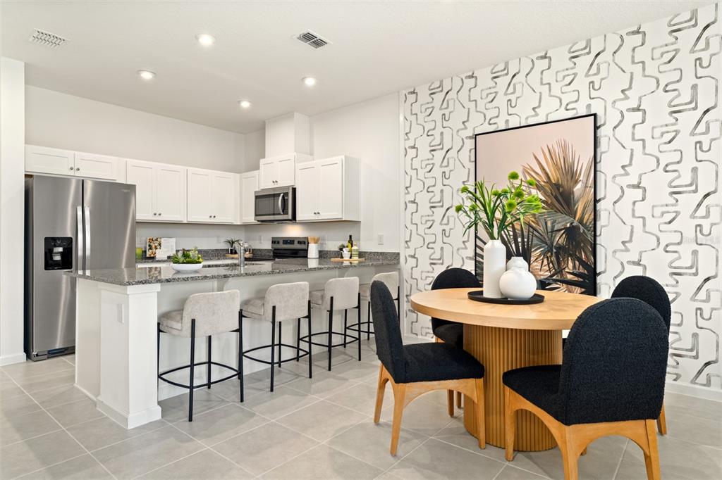 A kitchen and dining area with white cabinets, granite countertops, and patterned wallpaper — 2808 CAMELLIA FLOWER STREET, APOPKA, FL