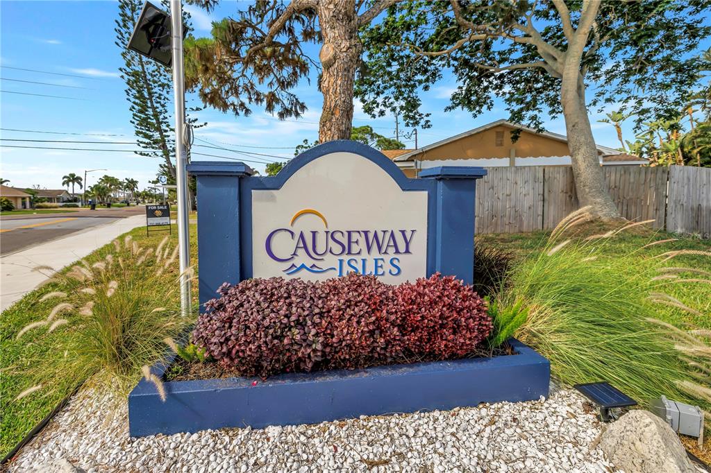 A blue monument sign for Causeway Isles stands in a landscaped bed with white gravel — 7901 CAUSEWAY BOULEVARD S, ST PETERSBURG, FL