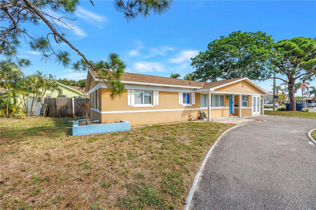 A single-story yellow house with a curved driveway and a blue planter box — 7901 CAUSEWAY BOULEVARD S, ST PETERSBURG, FL