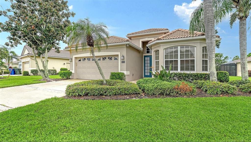 A single-story suburban house with a tan stucco exterior, tile roof, and a two-car garage — 8224 NICE WAY, SARASOTA, FL
