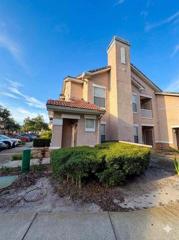 A two-story tan stucco apartment building features a tiled roof and a prominent chimney — 10467 VILLA VIEW CIRCLE UNIT 10467, TAMPA, FL