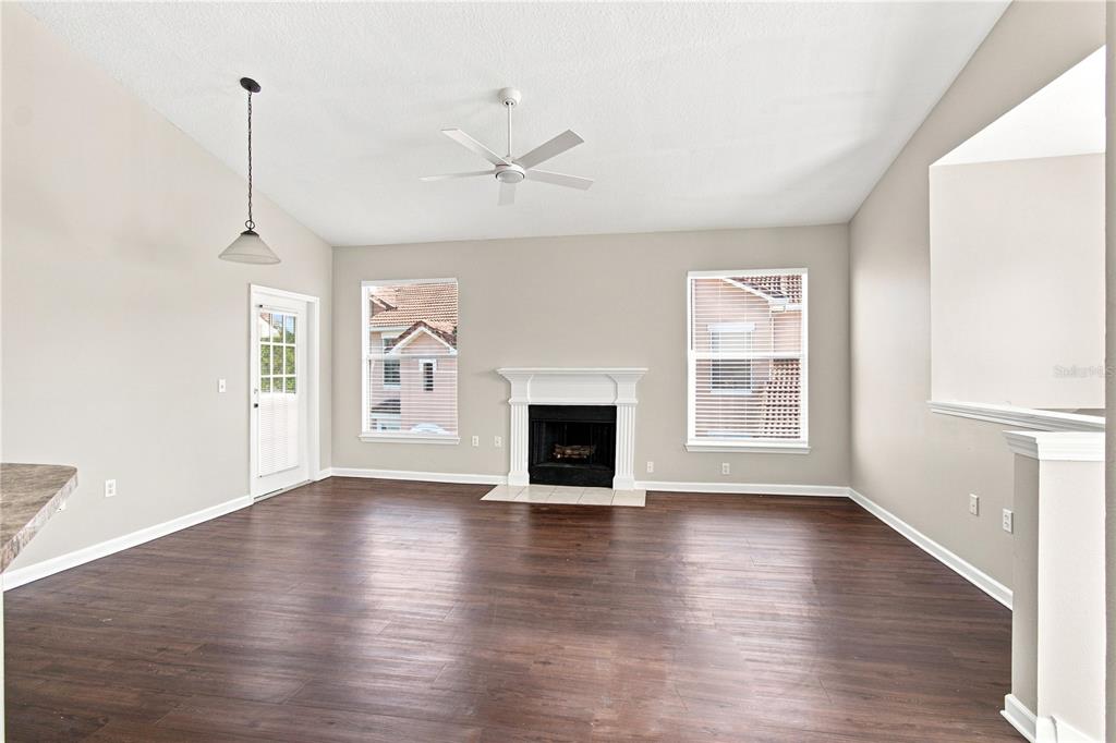 A living room features dark wood flooring, a fireplace, a ceiling fan, and two windows — 10467 VILLA VIEW CIRCLE UNIT 10467, TAMPA, FL