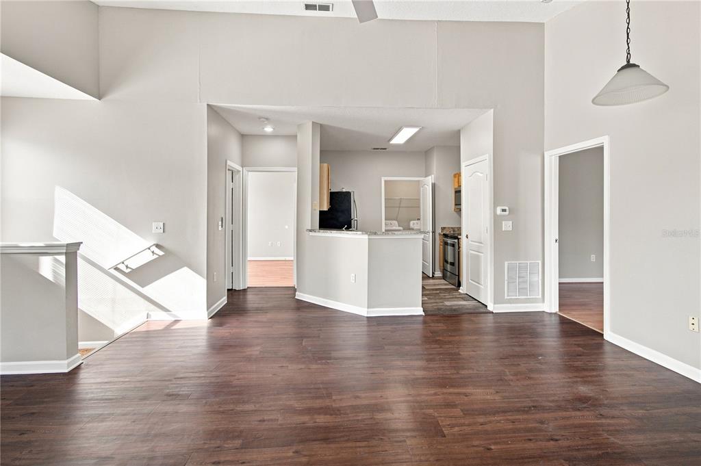 An open-concept living area features dark wood-look flooring, a kitchen peninsula, and high ceilings — 10467 VILLA VIEW CIRCLE UNIT 10467, TAMPA, FL