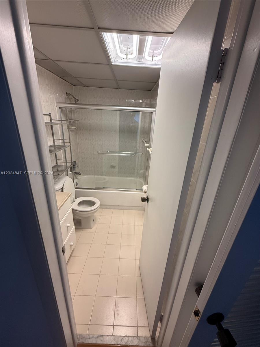 A bathroom features a tub-shower combination, a white vanity, and a drop ceiling with lighting — 2201 Brickell Ave # 67C, Miami FL 33129, MIAMI, FL