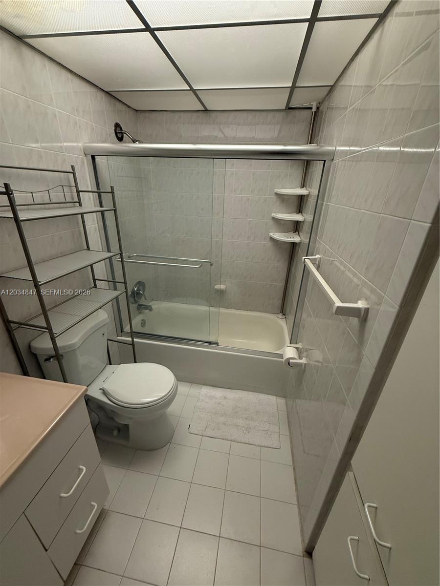 A bathroom features a tiled tub-shower combination, a toilet, and a metal shelving unit — 2201 Brickell Ave # 67C, Miami FL 33129, MIAMI, FL