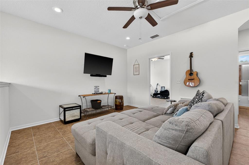 A living room features a grey sectional sofa, a wall-mounted television, and tile flooring — 3204 W MARLIN AVENUE, TAMPA, FL