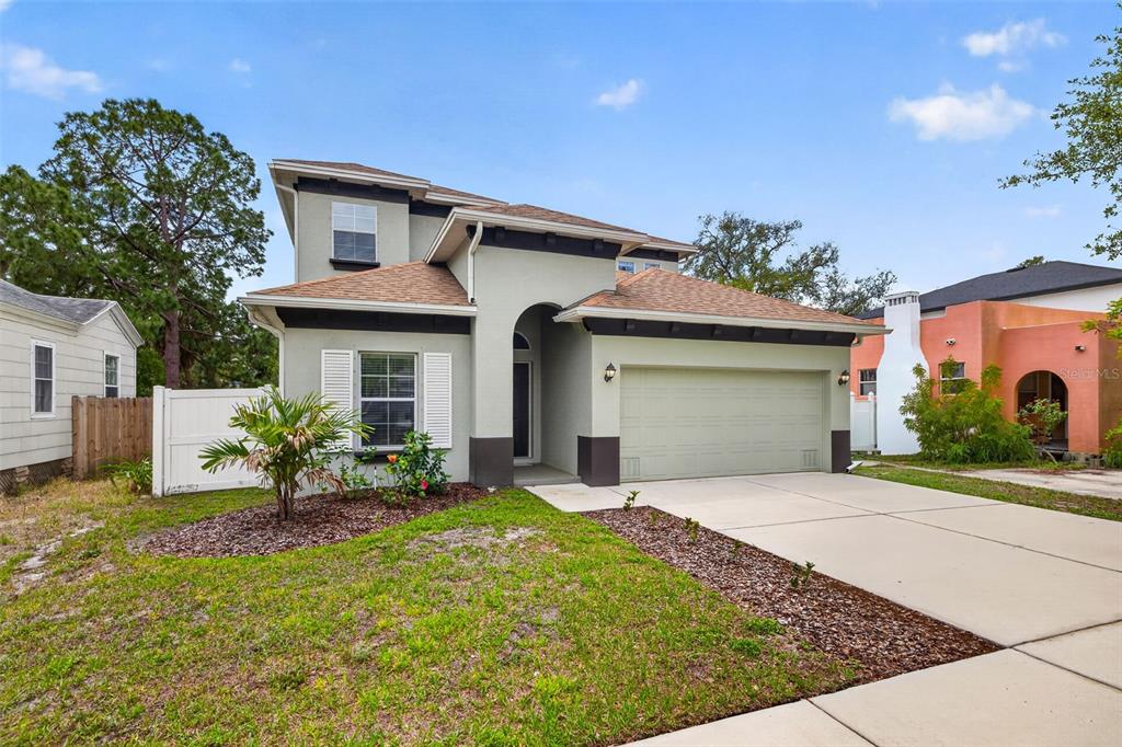 A two-story house with a light-colored stucco exterior, a two-car garage, and a front lawn — 3204 W MARLIN AVENUE, TAMPA, FL