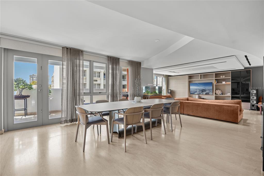 A dining area with a long table and chairs opens to a balcony and living room — 63 MIRSONIA STREET UNIT 401, SAN JUAN, PR
