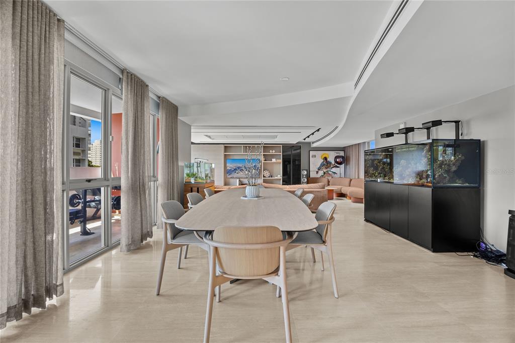 A dining area with a long table, chairs, and a large aquarium on a tile floor — 63 MIRSONIA STREET UNIT 401, SAN JUAN, PR