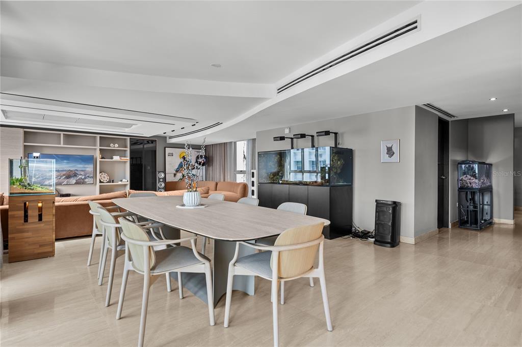 A dining area with a light wood table, modern chairs, and multiple fish tanks — 63 MIRSONIA STREET UNIT 401, SAN JUAN, PR