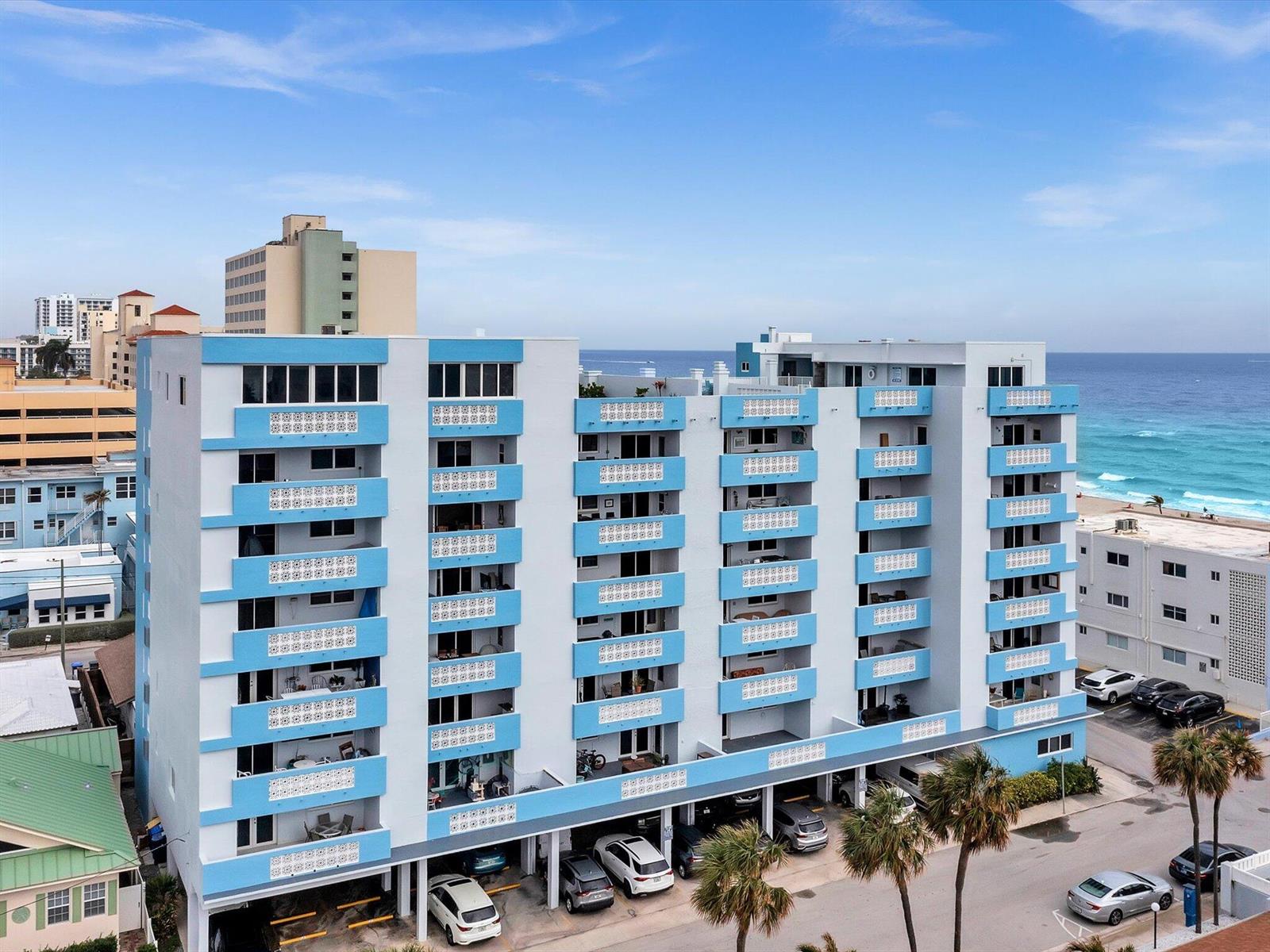 An exterior view of a multi-story apartment building with blue and white balconies near the ocean — 320 S Surf Road # 205, Hollywood FL 33019, HOLLYWOOD, FL