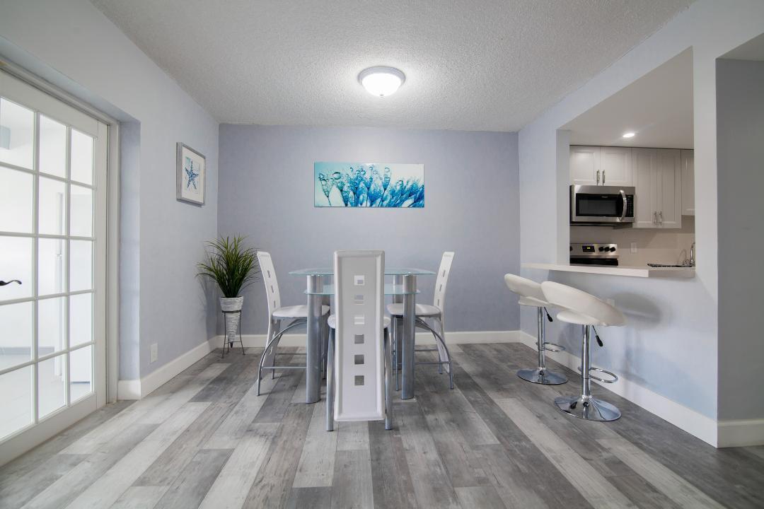 A dining area with a glass table, white chairs, and gray wood-look flooring — 320 S Surf Road # 205, Hollywood FL 33019, HOLLYWOOD, FL